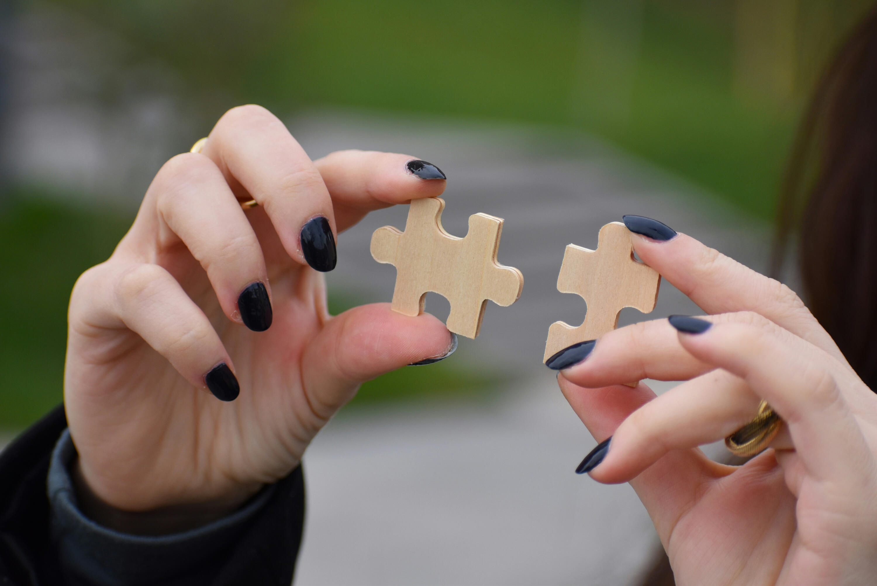 Woman's hands, each holding a puzzle piece. Pieces are held in mid-air as the hands align the two pieces together. For project managers who are ready to integrate GenAI into their workflow. Tagline: Collaborating - Working Alongside AI. Source: Paul Stefan